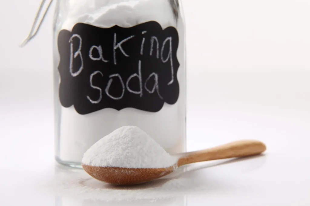 Barattolo di vetro etichettato Baking Soda con un cucchiaio di legno utile per rimuovere macchie di curcuma dai mobili della cucina