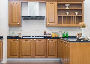 Traditional kitchen with wood stained cabinets and black countertops showcasing various bottles and jars with a decorative range hood