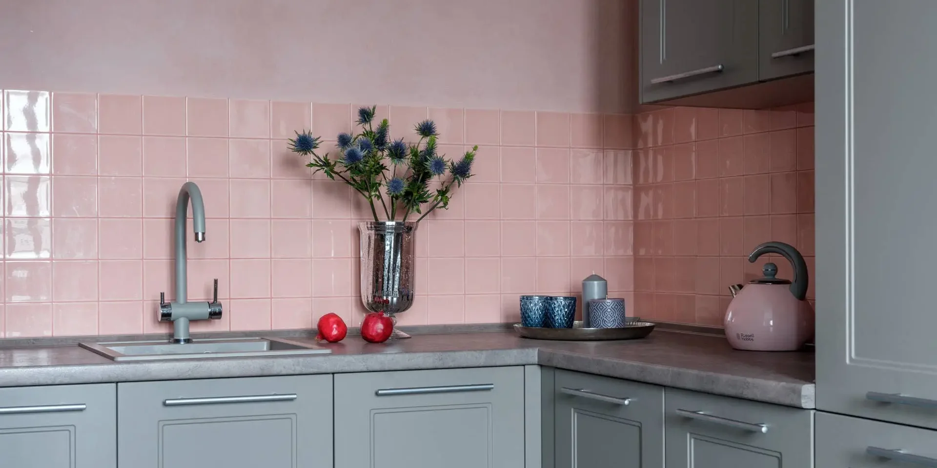 La parete rosa si abbina ai mobili da cucina grigi