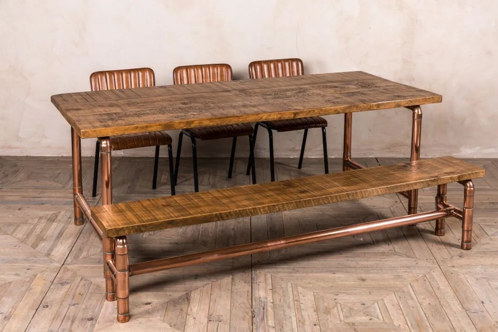 Industrial style dining table with wooden top and pipe legs paired with metal chairs
