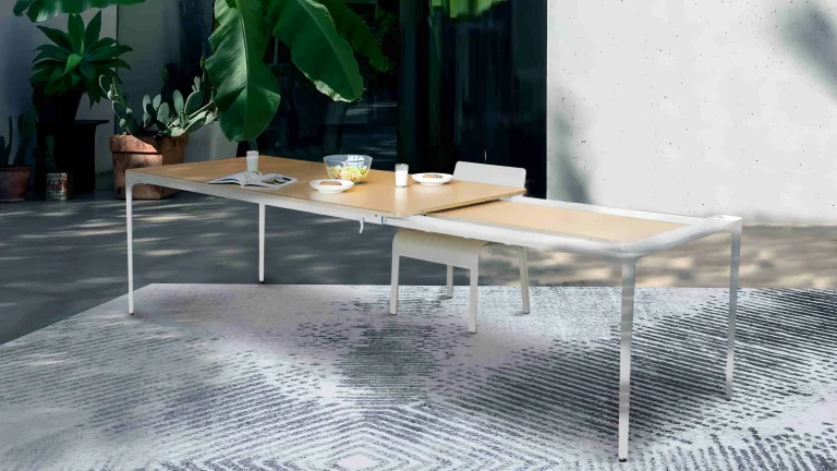 Spacious patio with an extendable outdoor dining table surrounded by lush plants and natural light