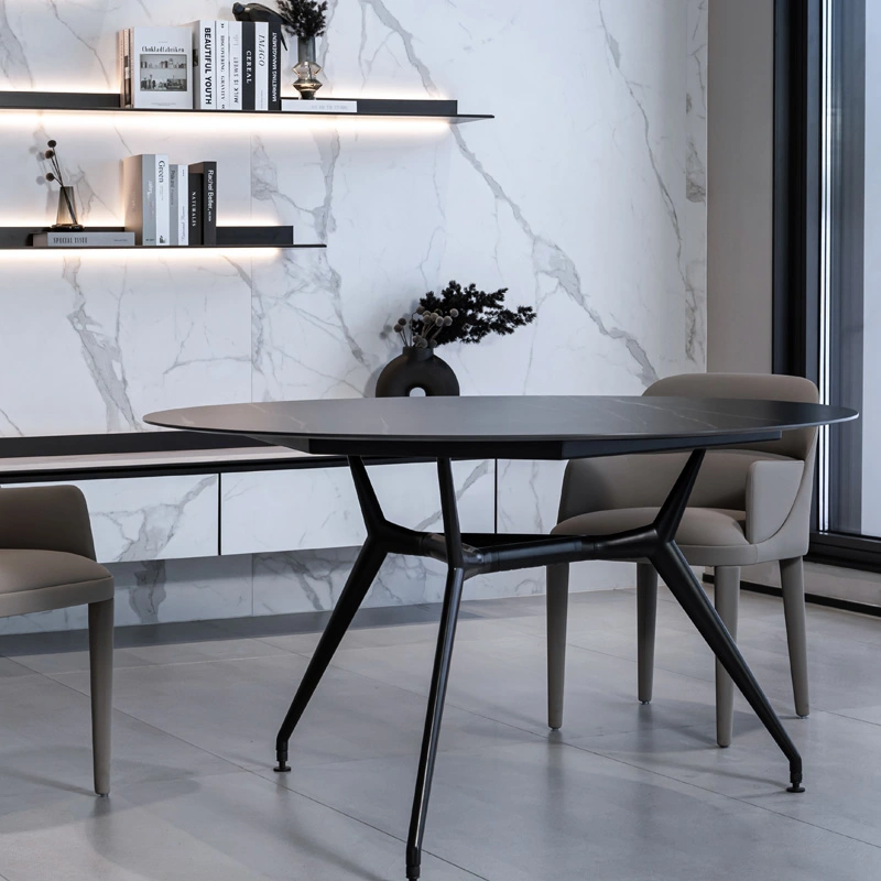 Round black ceramic table with marble wall in background Light fixture hangs from ceiling