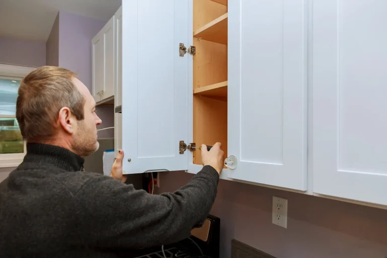 a man is adjusting the hinges of a white kitchen cabinet door to ensure it closes properly