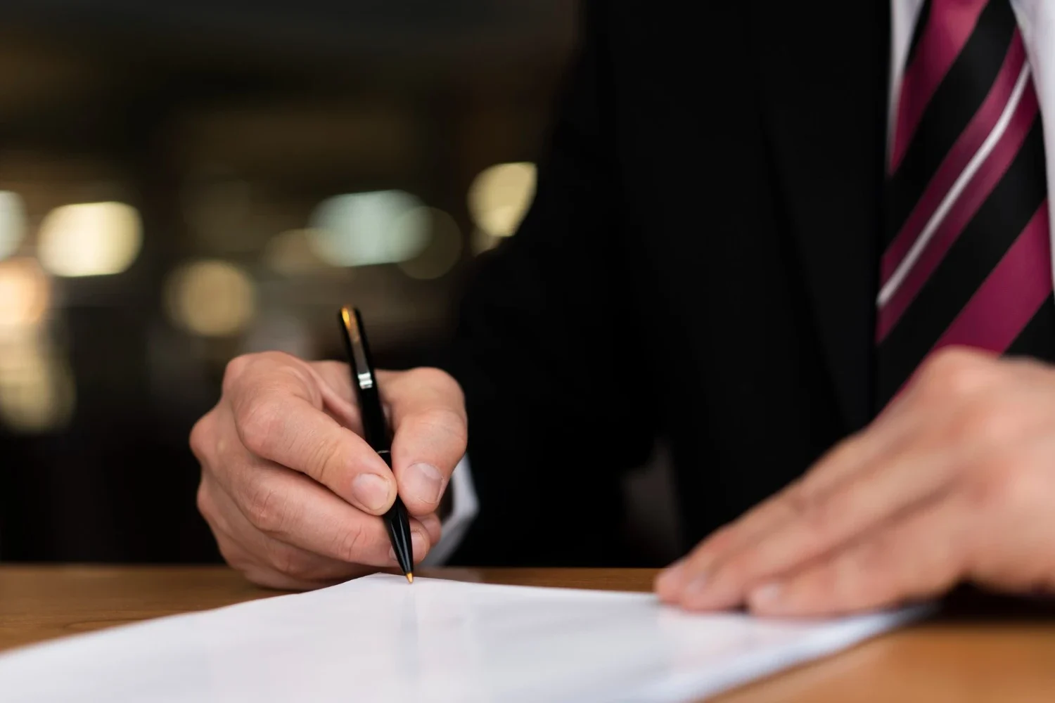 Close up of a man in a suit signing a contract