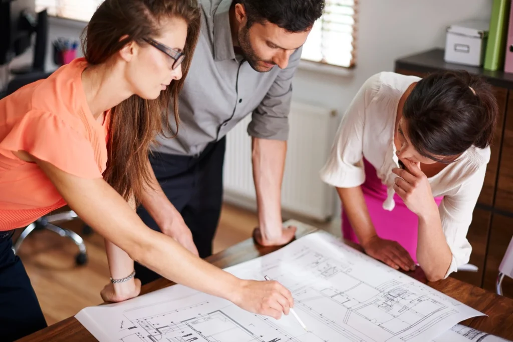 Designers examining architectural blueprints at a table
