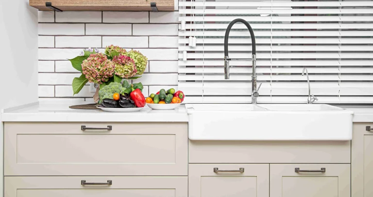 white kitchen cabinets with metal handles doors near washbasin with bouquet flowers plate vegetables