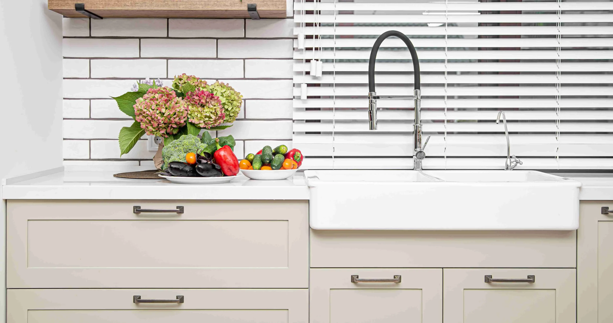 white kitchen cabinets with metal handles doors near washbasin with bouquet flowers plate vegetables