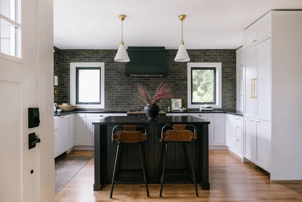 Cozy kitchen with vintage pendant lights white cabinetry and black counters Cozy kitchen with vintage pendant lights white cabinetry and black counters
