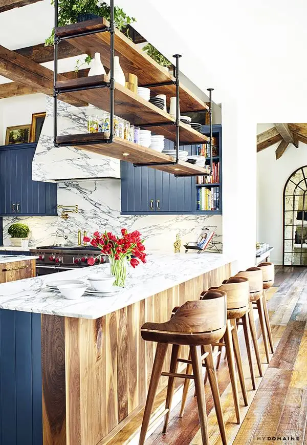 Floating shelves with greenery above a modern kitchen island Floating shelves with greenery above a modern kitchen island