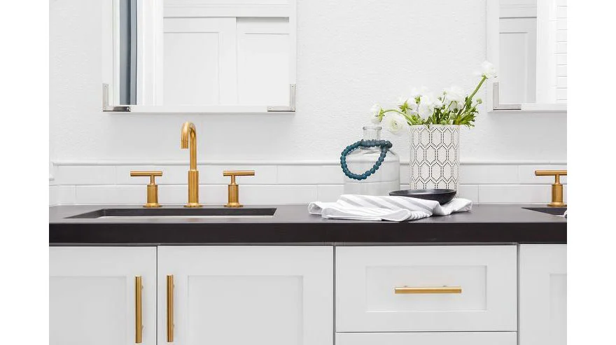 Gold fixtures white cabinets and black countertops in a modern kitchen Gold fixtures white cabinets and black countertops in a modern kitchen