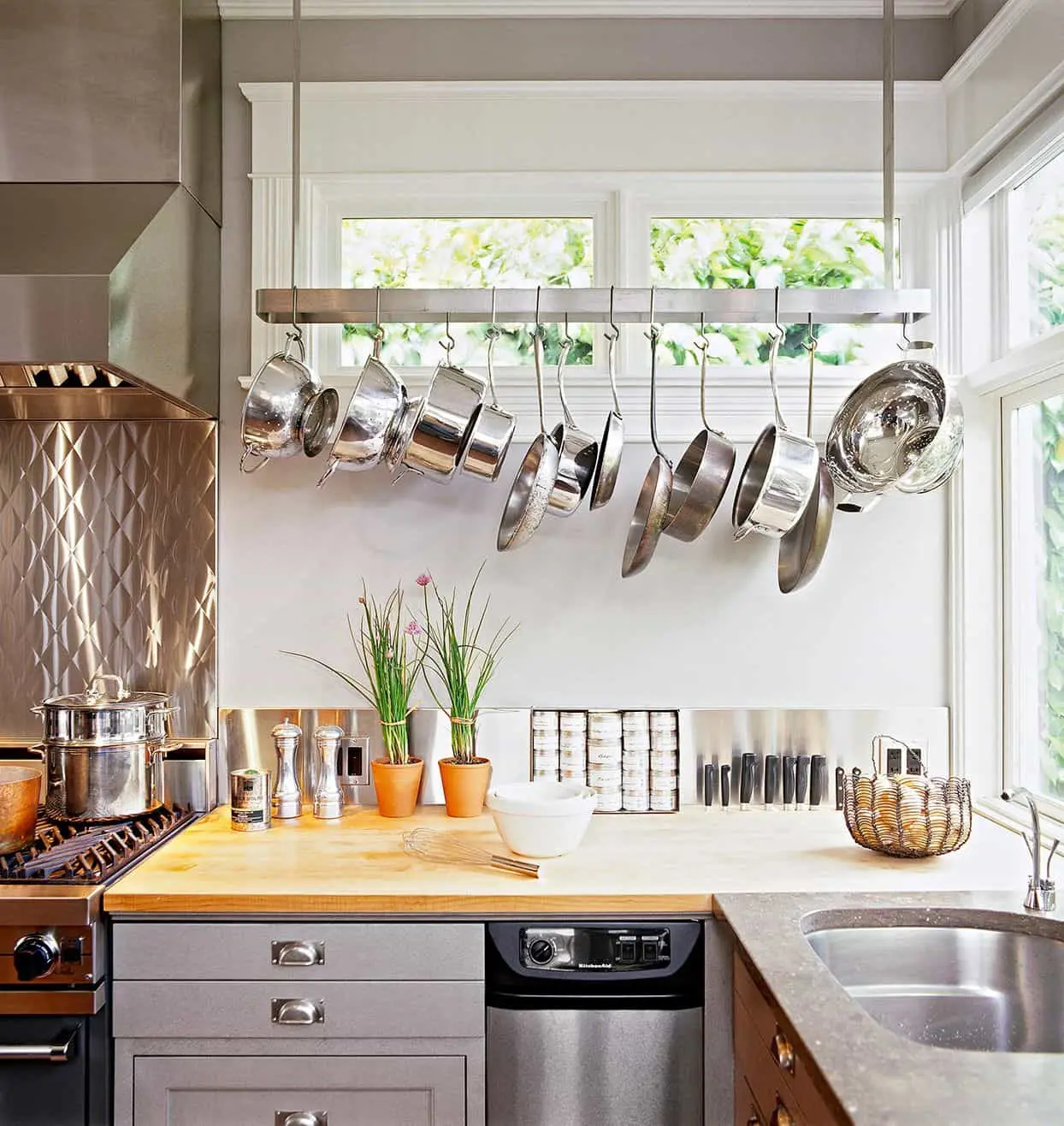 Hanging pot rack with stainless steel cookware in a bright kitchen
