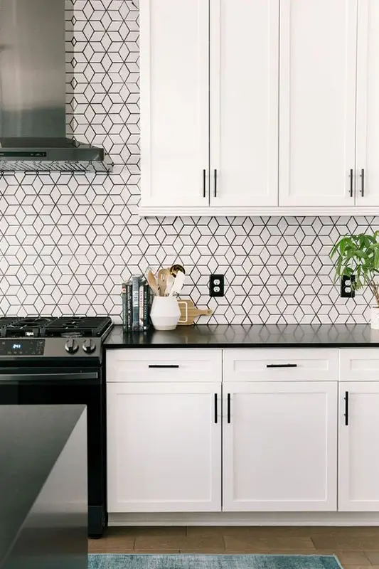 Kitchen with geometric patterned backsplash white cabinets and black countertops Kitchen with geometric patterned backsplash white cabinets and black countertops