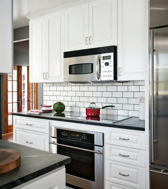 Kitchen with white cabinets black countertops and subway tiles with black grout Kitchen with white cabinets black countertops and subway tiles with black grout