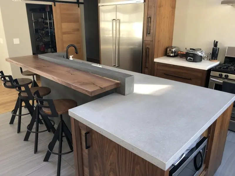 Modern kitchen featuring Concrete Countertops with integrated wood bar and warm wood cabinetry Modern kitchen featuring Concrete Countertops with integrated wood bar and warm wood cabinetry