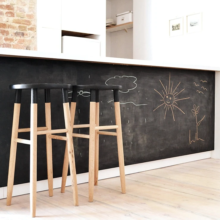 Modern kitchen island with interactive chalkboard panels and wooden bar stools Modern kitchen island with interactive chalkboard panels and wooden bar stools
