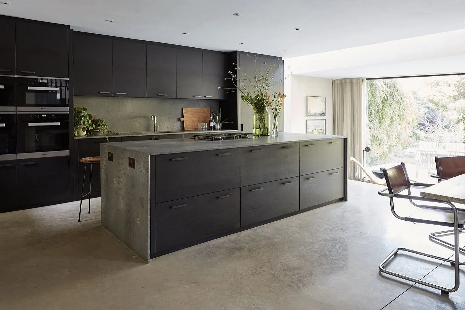 Cocina moderna con gabinetes oscuros y elegantes encimeras de concreto que brindan luz natural. Cocina moderna con gabinetes oscuros y elegantes encimeras de concreto que brindan luz natural.