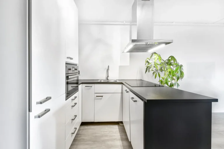 Modern kitchen with white cabinets black countertops and stainless steel accents