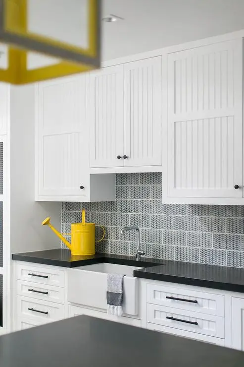 White beadboard cabinets with black countertops in a modern kitchen White beadboard cabinets with black countertops in a modern kitchen