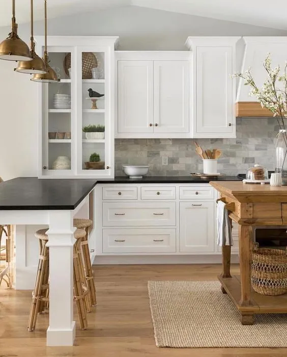 White cabinets and black countertops complemented by patterned tiles in the kitchen White cabinets and black countertops complemented by patterned tiles in the kitchen