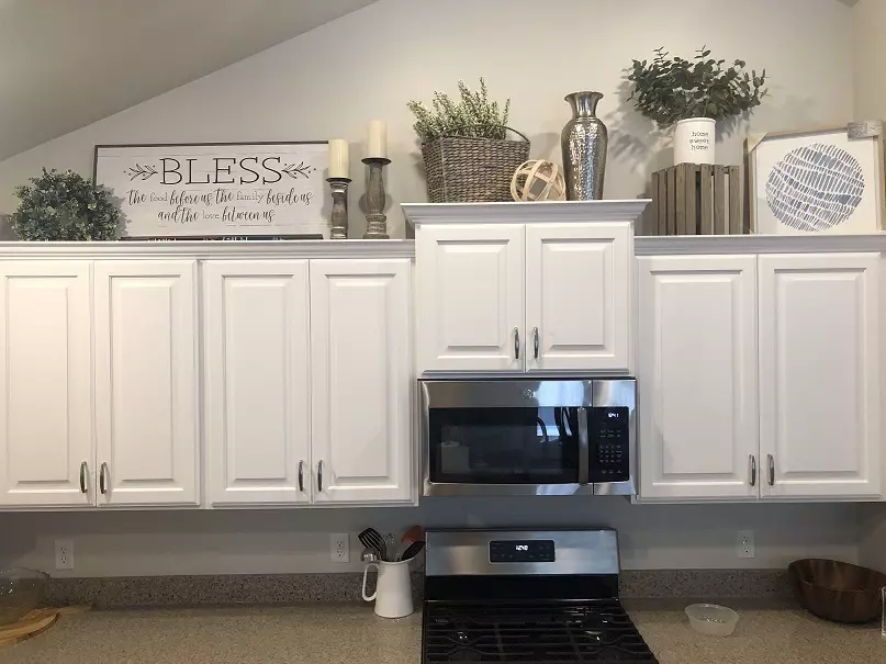 Decorative sign plants and vases displayed above white cabinets