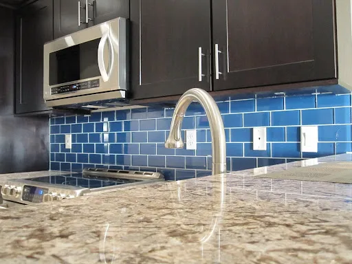 Modern kitchen with blue subway tile backsplash and dark cabinetry Modern kitchen with blue subway tile backsplash and dark cabinetry