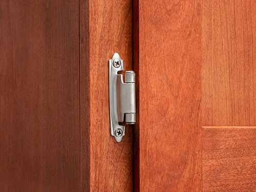Stainless steel hinge on a wooden kitchen cabinet with a classic look Stainless steel hinge on a wooden kitchen cabinet with a classic look