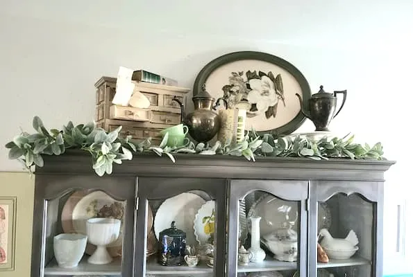 Decoración vintage y vegetación exhibida sobre una vitrina de vidrio.