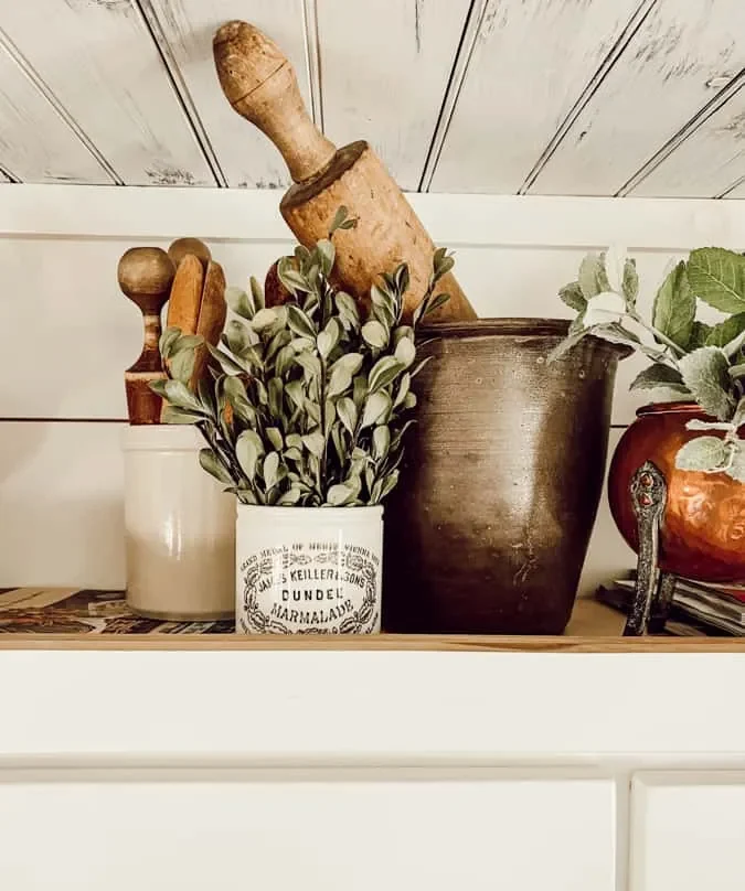 Herramientas de cocina antiguas y plantas sobre gabinetes de cocina de estilo rústico