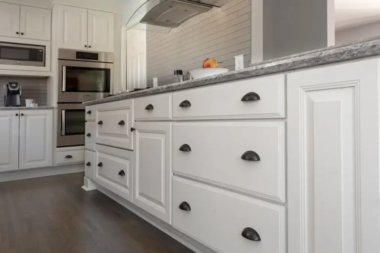 White kitchen cabinets with dark cup handles and a grey countertop
