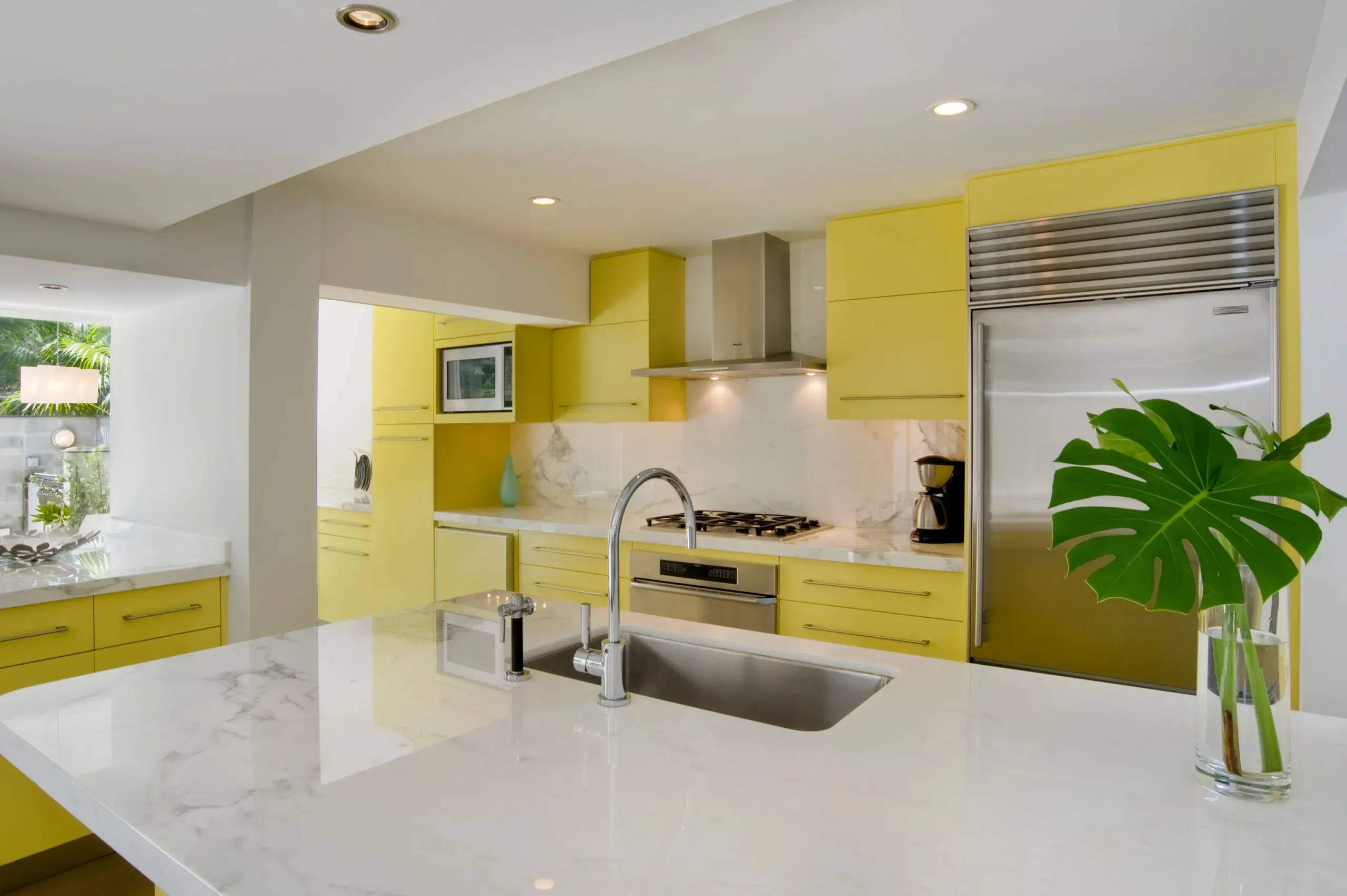 Bright yellow kitchen cabinets with white countertops and sink