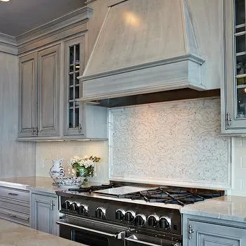 Gray toned antiqued kitchen with decorative backsplash and stove Gray toned antiqued kitchen with decorative backsplash and stove