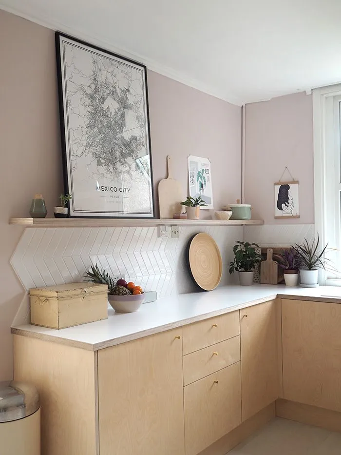 Light wood cabinets with modern decor and soft pink wall accents Light wood cabinets with modern decor and soft pink wall accents