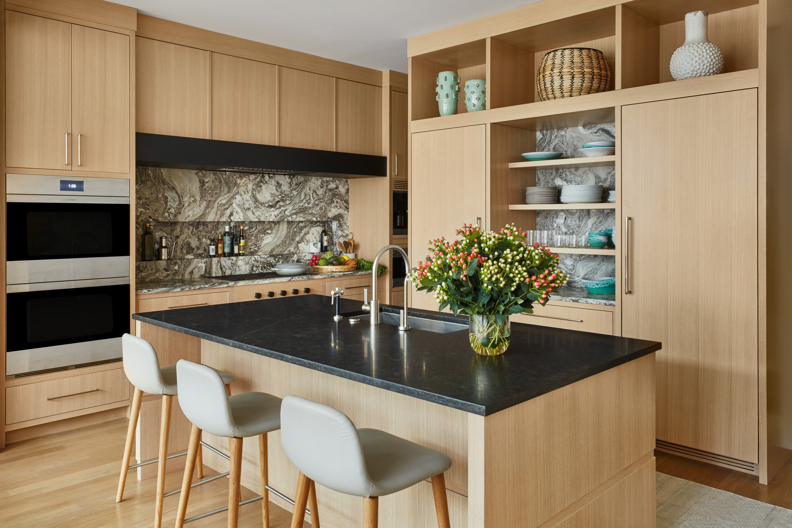 Light wooden kitchen with black countertops and decorative vases Light wooden kitchen with black countertops and decorative vases