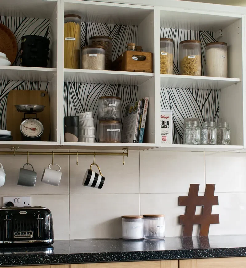 Organized kitchen shelves with labeled jars and mugs Organized kitchen shelves with labeled jars and mugs