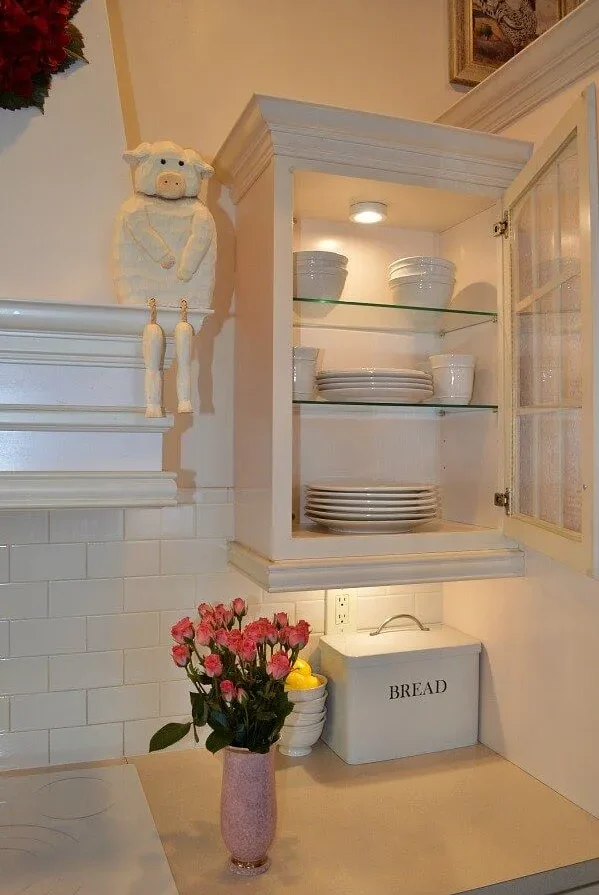 White cabinet with glass doors displaying dishes in a cozy kitchen White cabinet with glass doors displaying dishes in a cozy kitchen