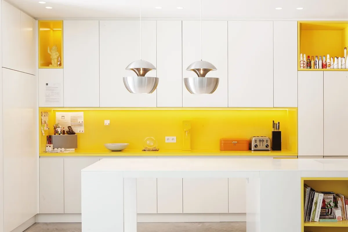 White kitchen with bright yellow backsplash and hanging lights