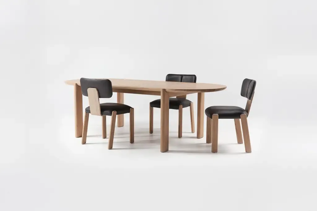 Jardan dining table with rounded edges and four black cushioned chairs