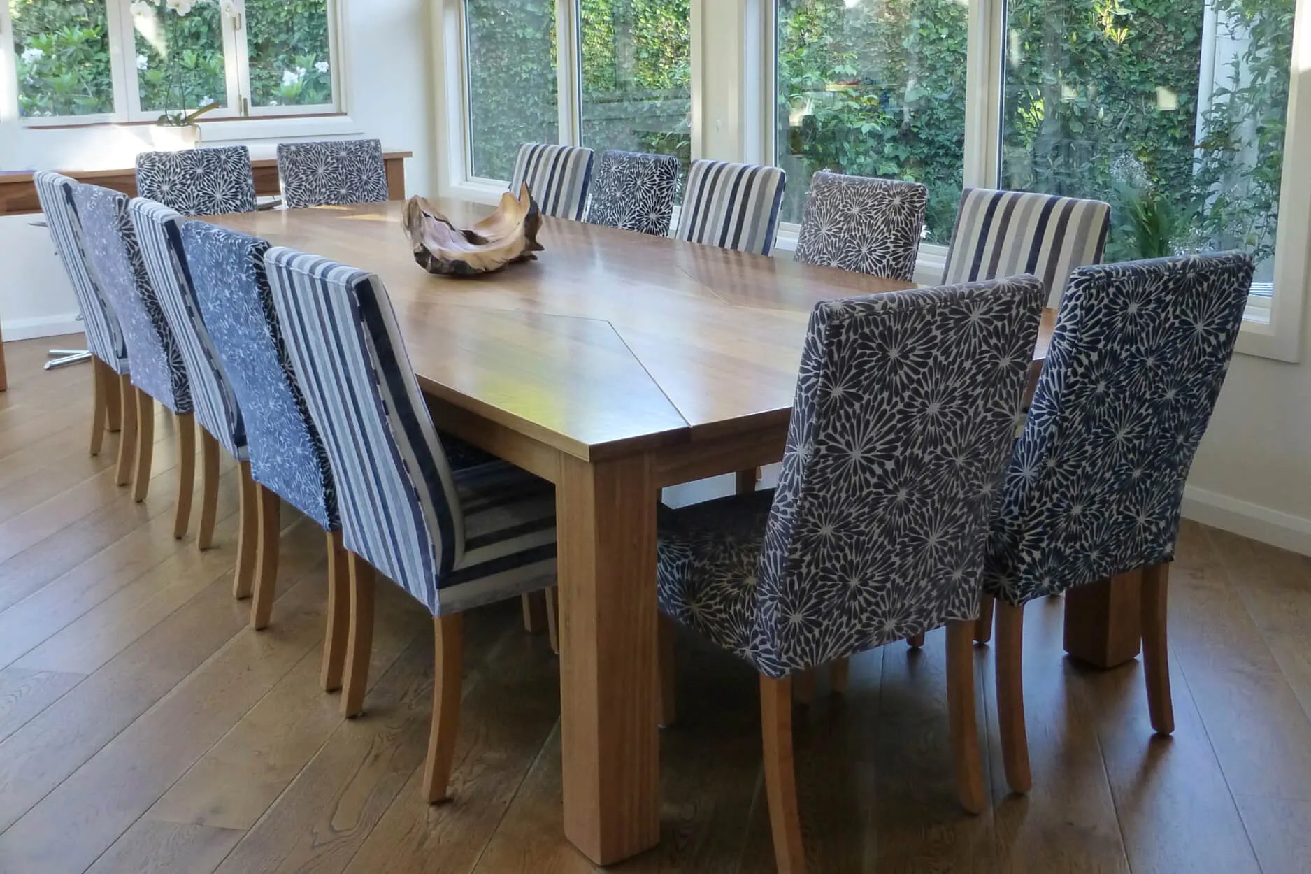 Large dining table surrounded by striped and floral patterned chairs
