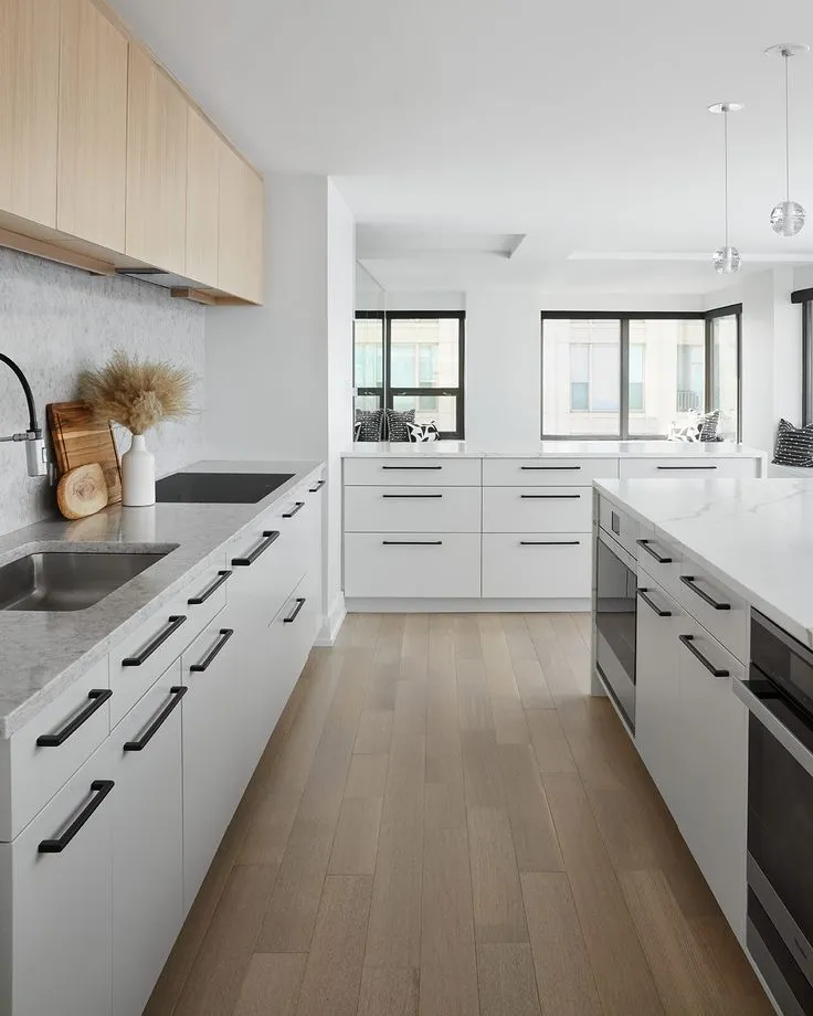 Stylish modern white kitchen featuring black handles and knobs