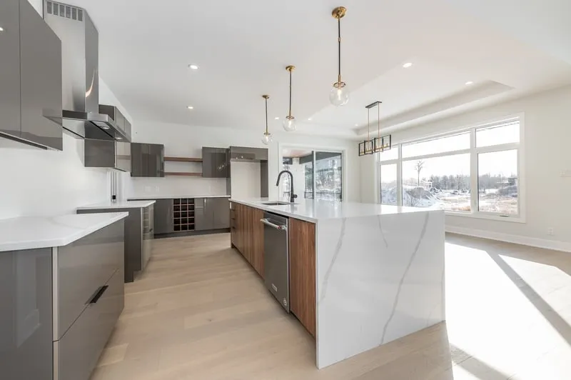 Open kitchen with a large white waterfall island and pendant lights Open kitchen with a large white waterfall island and pendant lights