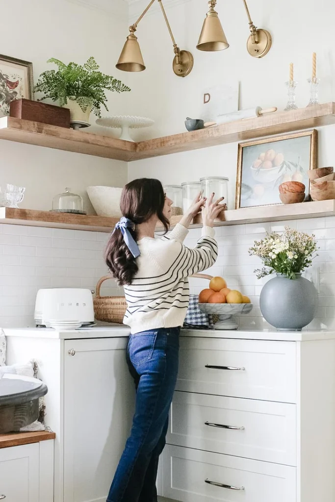 Woman organizing kitchen items on open shelve