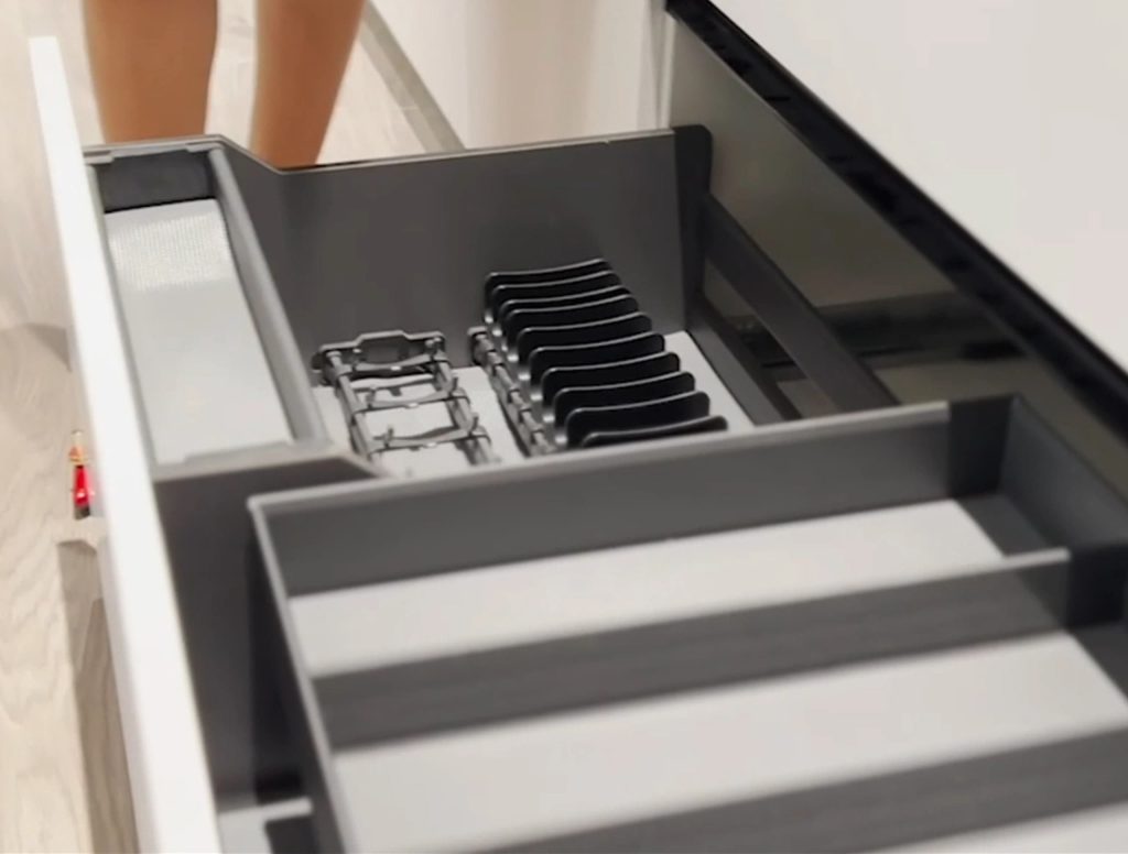 Close-up of drawer storage in Italian Kitchen Cabinet with kitchenware.